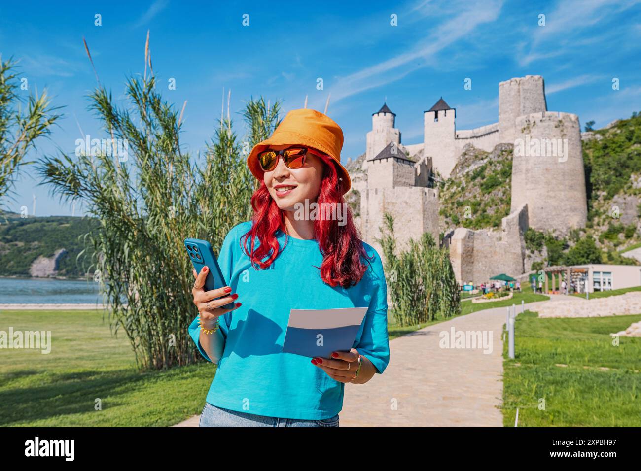 Eine Frau navigiert mit ihrem Smartphone zur Festung Golubac in Serbien und sucht auf ihrer Karte nach der besten Route, um Architektur und Geschichte zu erkunden Stockfoto