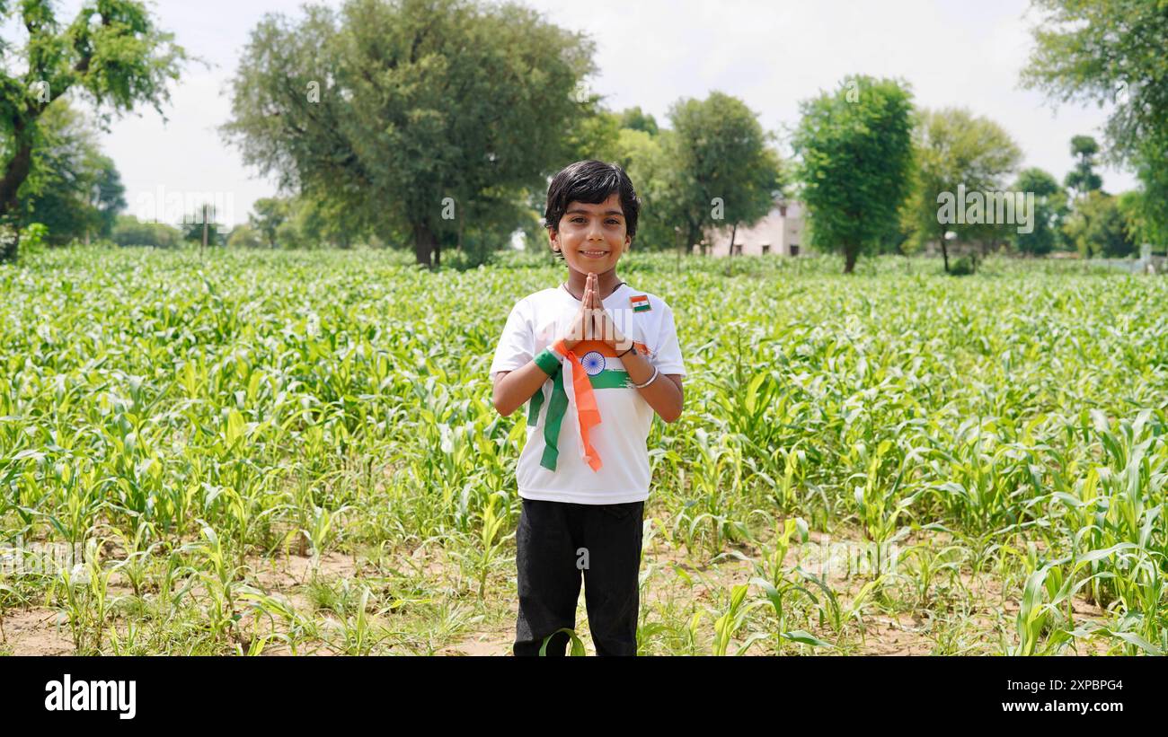 Kinder mit Familienmitgliedern tragen T-Shirt mit indischer Flagge und halten, winken oder laufen mit Tricolor mit Grün im Hintergrund, feiern Stockfoto