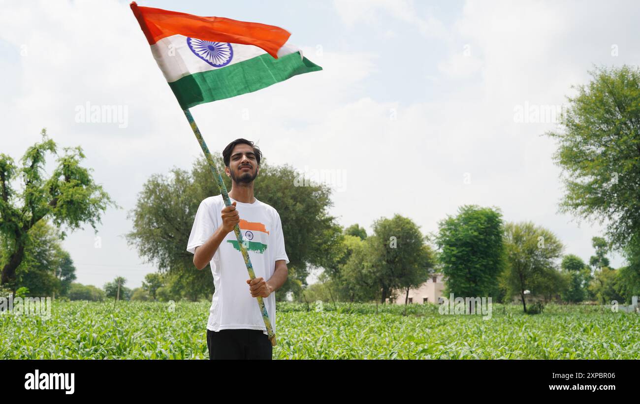 Kinder mit Familienmitgliedern tragen T-Shirt mit indischer Flagge und halten, winken oder laufen mit Tricolor mit Grün im Hintergrund, feiern Stockfoto