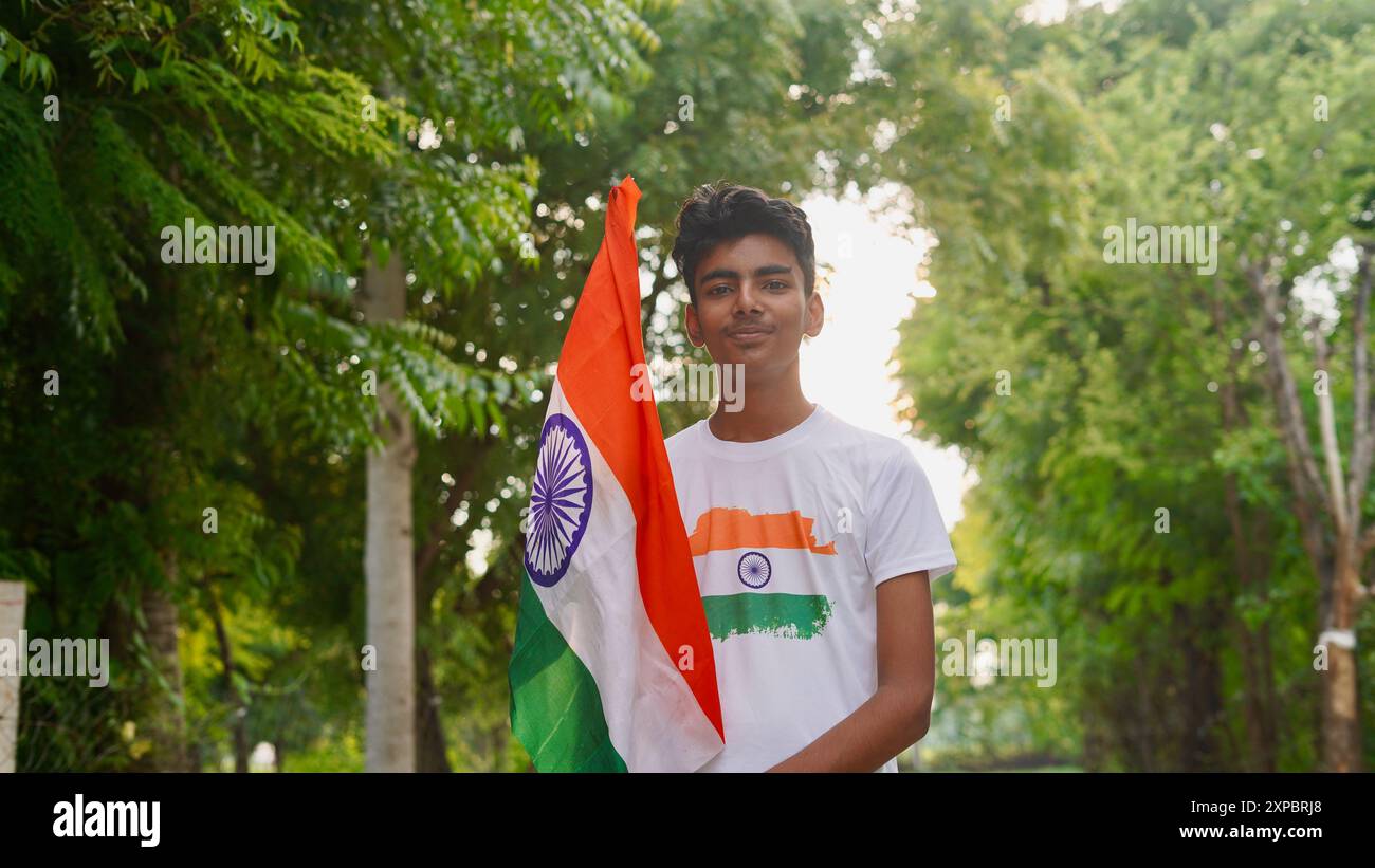 Kinder mit Familienmitgliedern tragen T-Shirt mit indischer Flagge und halten, winken oder laufen mit Tricolor mit Grün im Hintergrund, feiern Stockfoto