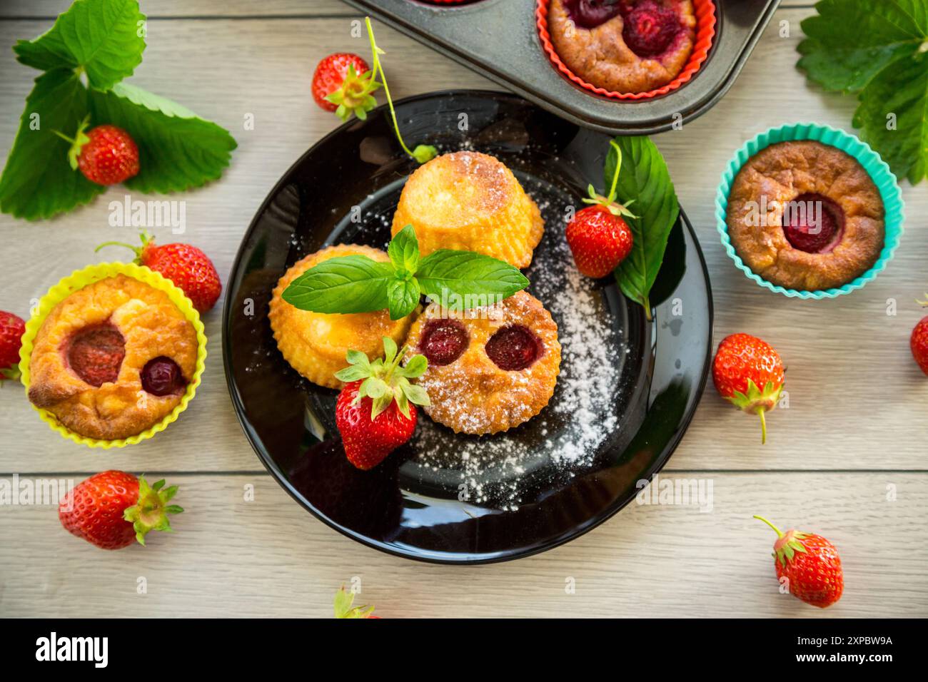 Süße Quark-Muffins mit Erdbeerfüllung, auf einem Teller auf einem Holztisch. Stockfoto
