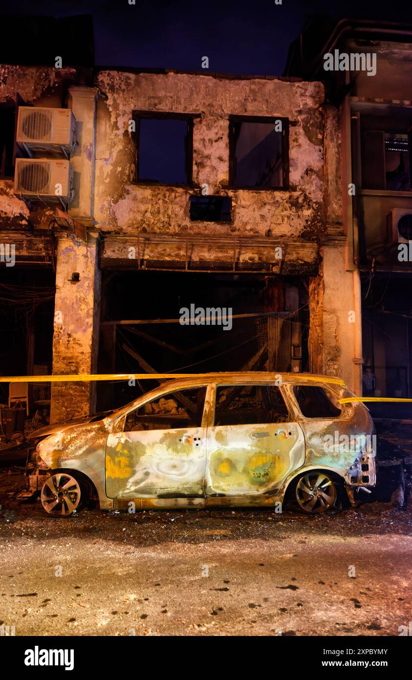 Altes chinesisches Ladenhaus, Feuer beschädigt durch den ausgebrannten Autorahmen davor, Carpenter Street, Kuching, Malaysia Stockfoto