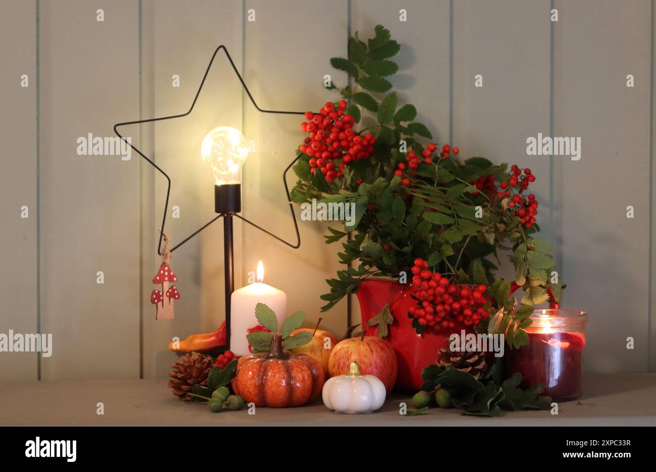 Weihnachtsdekoration auf einer Kommode mit Kerzen, vogelbeeren und einer sternförmigen LED-Laterne. Grüner Holzhintergrund mit Kopierraum. Stockfoto