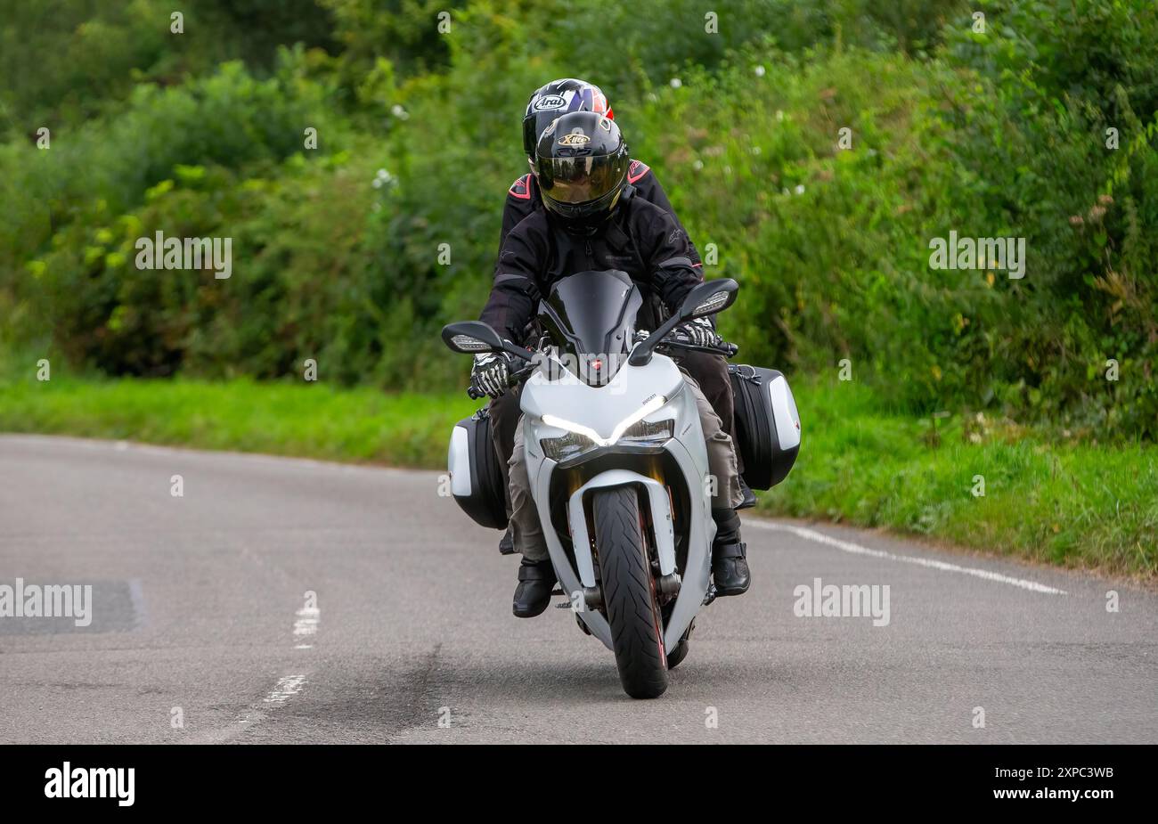 Whittlebury, Norhants, Großbritannien - 4. August 2024. Mann und Sozius, der ein 2018 weißes Ducati Supersport S Motorrad auf einer britischen Landstraße fährt Stockfoto