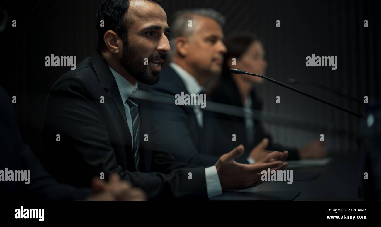 Multiethnische Männliche Leiter Der Politischen Delegation Auf Der Pressekonferenz Des Internationalen Wirtschaftsforums. Hochrangiger Politiker, Der Über Erfolgreiche Vereinbarungen Berichtet. Verschiedene Teilnehmer Hören Zu. Stockfoto