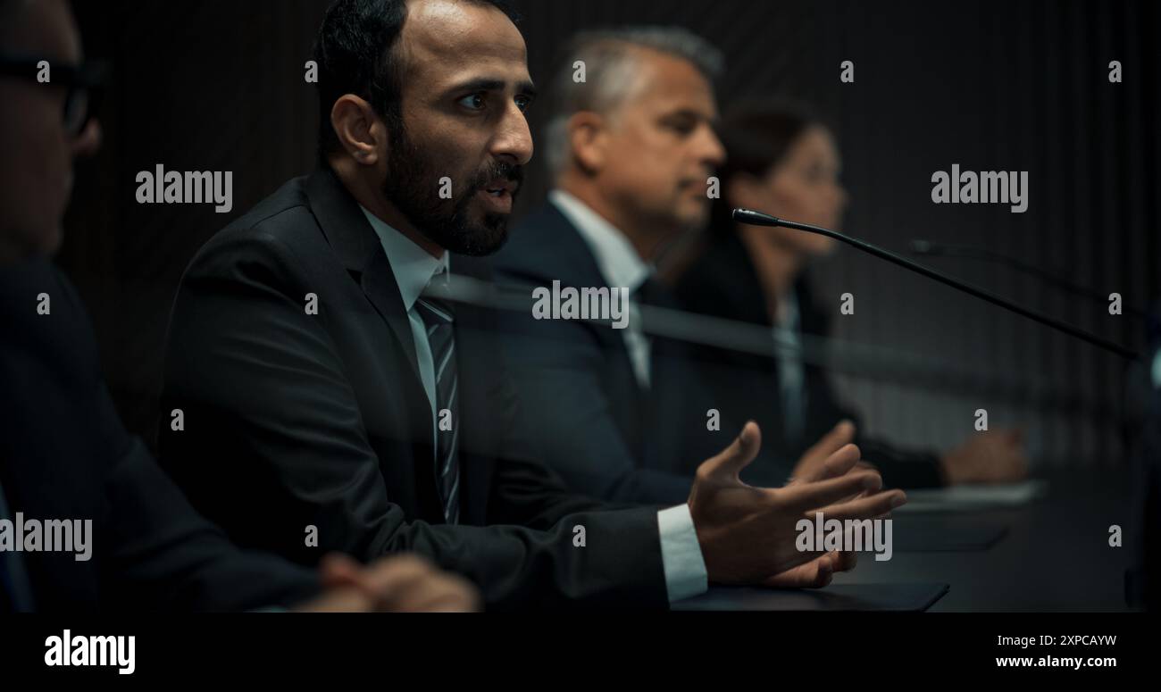 Multiethnische Männliche Leiter Der Politischen Delegation Auf Der Pressekonferenz Des Internationalen Wirtschaftsforums. Hochrangiger Politiker, Der Über Erfolgreiche Vereinbarungen Berichtet. Unterschiedliche Teilnehmer, Die Auf Unterschiedliche Weise Zuhören Stockfoto