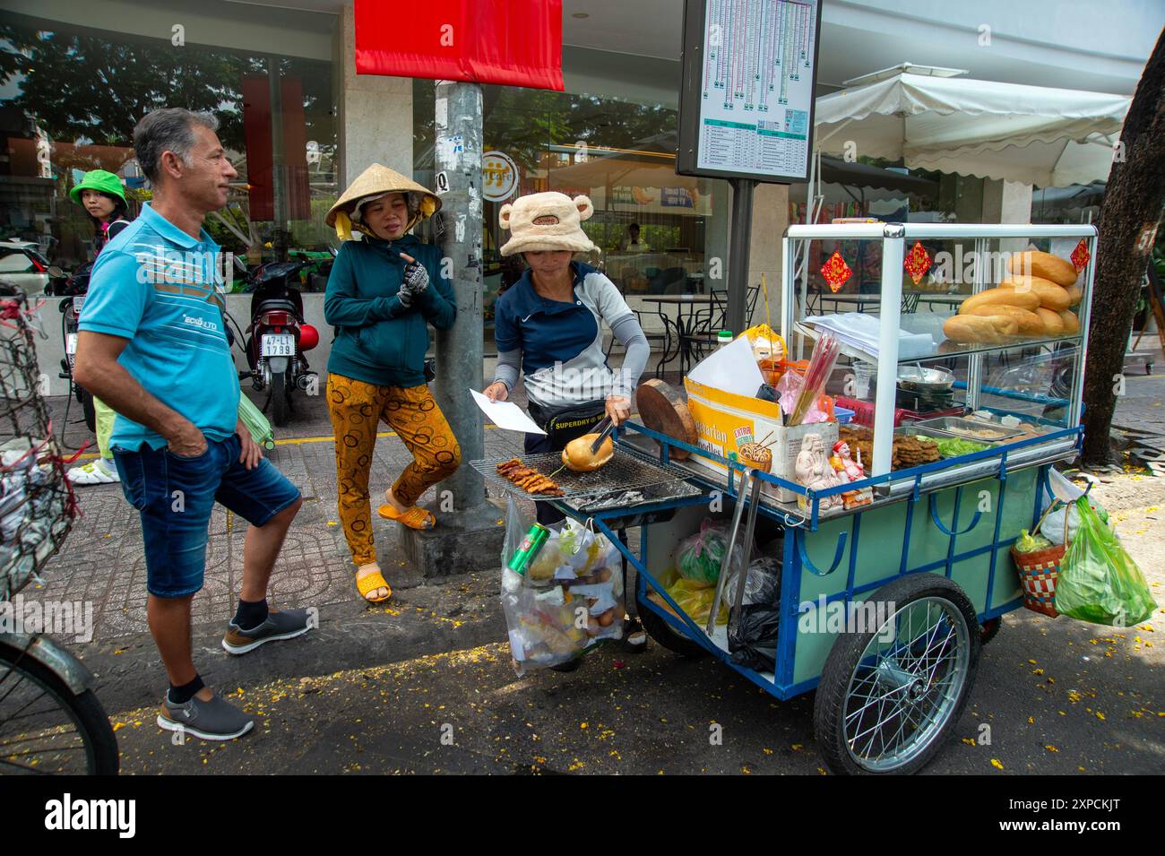 Ein Street Food-Händler, der Banh mi an einen europäischen Touristen verkauft, auf den Straßen des Pham Ngu Lao Bezirks Saigon Vietnam Stockfoto