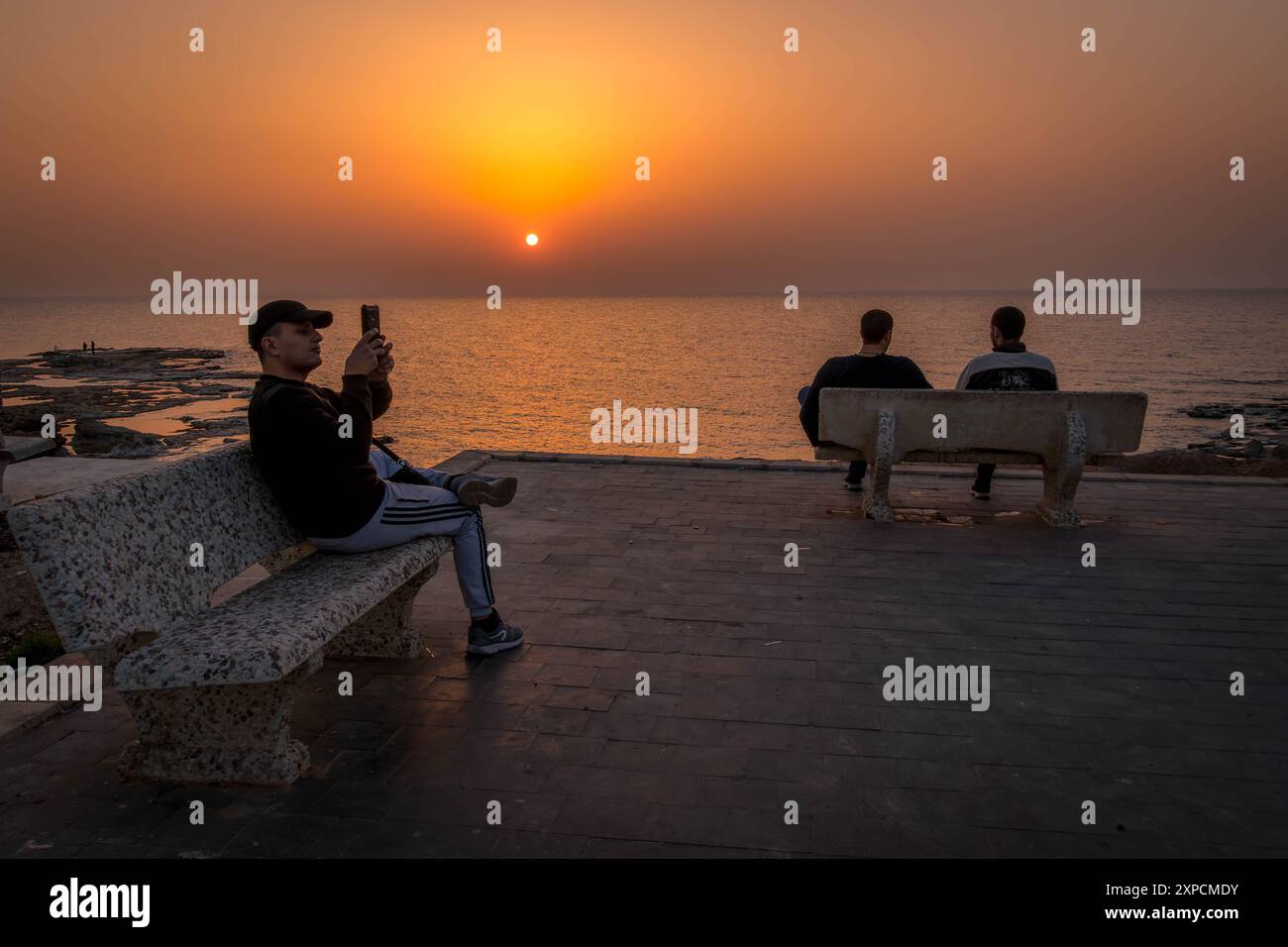 Die jungen libanesischen arabischen Männer am Ufer von Tyrus in Sour, Libanon, an der Mittelmeerküste während des farbenfrohen Sonnenuntergangs. Stockfoto