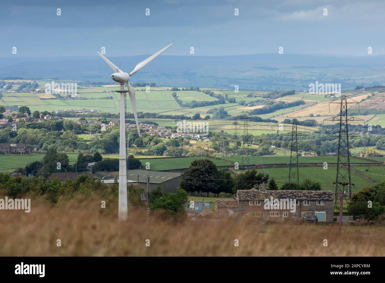 Pylonen und Windturbinen auf Ackerland und Feldern dominieren die Landschaft der Pennines zwischen Queensbury und Denholme in West Yorkshire, Großbritannien. Great British Energy bildet mit Investitionen in Höhe von 8 Mrd. GBP das Kernstück des Versprechens von Labour, die Stromversorgung bis 2030 zu dekarbonisieren. Dies würde bei weitem vor jeder Form der Renationalisierung enden: GB Energy wäre ein staatseigenes Investmentvehikel und Unternehmen, das neben und oft in Partnerschaft mit den bestehenden Anbietern des privaten Sektors zusammenarbeitet. Quelle: Windmill Images/Alamy Live News Stockfoto