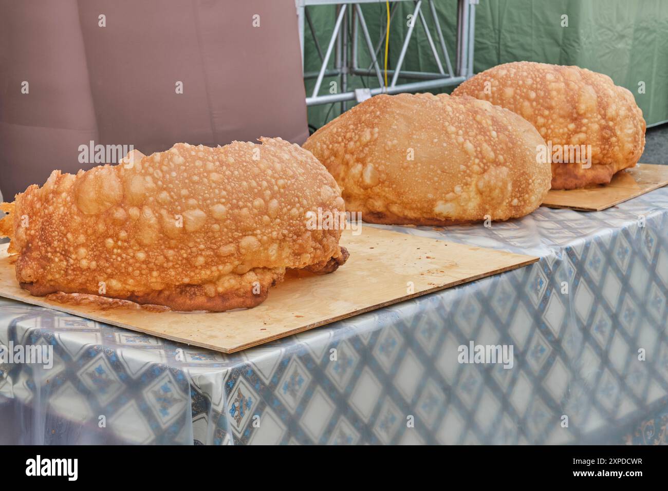 Drei riesige Baursaks, flauschige Teigstücke, frittiert, liegen während des größten Baursak-Wettbewerbs auf dem Tisch. Tatar gastronomisches Festival Sibirischer Baursa Stockfoto
