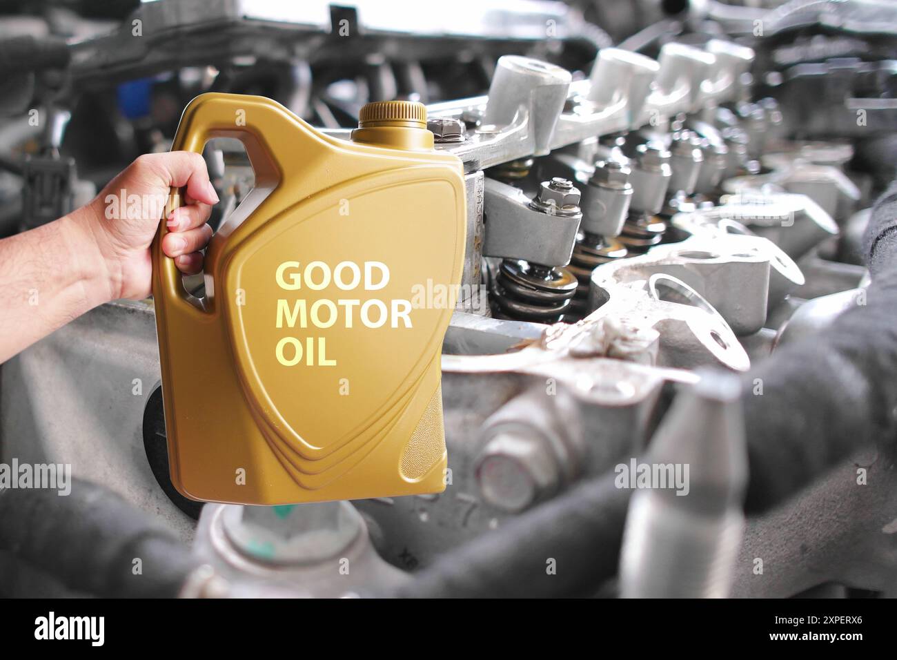 Konzept der Wahl eines guten Motoröls, die Mechaniker halten leistungsstarkes Motoröl mit Nahaufnahme des sauberen Motorinnenraums im Hintergrund. Stockfoto