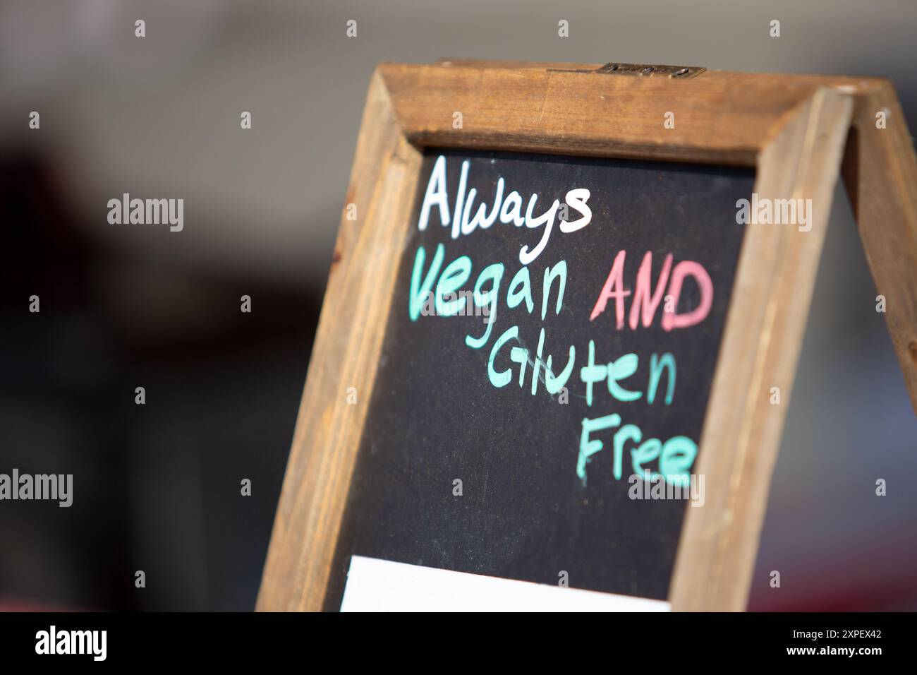 Ein Schild auf der Tafel zeigt den Kunden an, dass Lebensmittel immer vegan und glutenfrei sind. Stockfoto