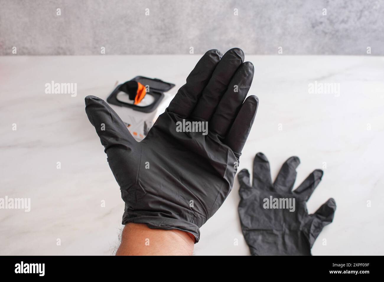 Ein Blick auf eine Hand, die einen schwarzen Nitril-Einweghandschuh trägt. Stockfoto