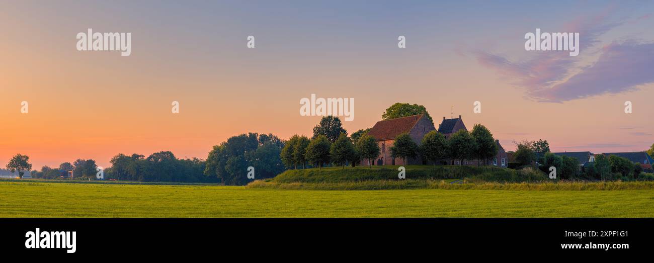Ein breites 3:1 Panoramabild von einem Sonnenaufgang in Ezinge, einem Dorf in der niederländischen Provinz Groningen. Sie befindet sich in der Gemeinde Westerkwartier, Stockfoto