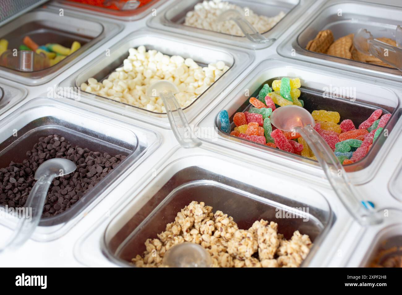 Ein Blick auf mehrere Behälter voller Beläge in einem gefrorenen Joghurt oder einer Eisdiele. Stockfoto