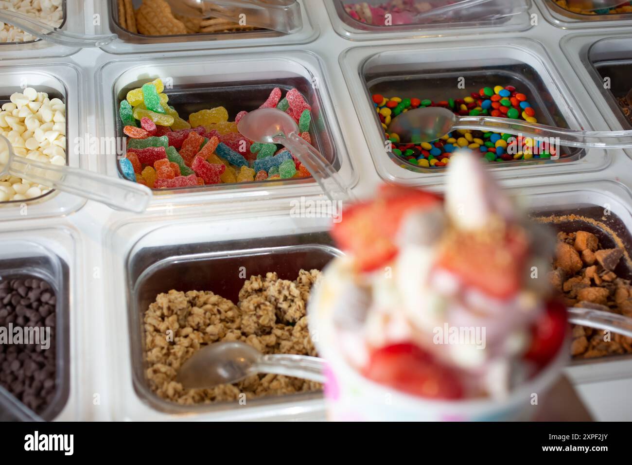 Ein Blick auf mehrere Behälter voller Beläge in einem gefrorenen Joghurt oder einer Eisdiele. Stockfoto