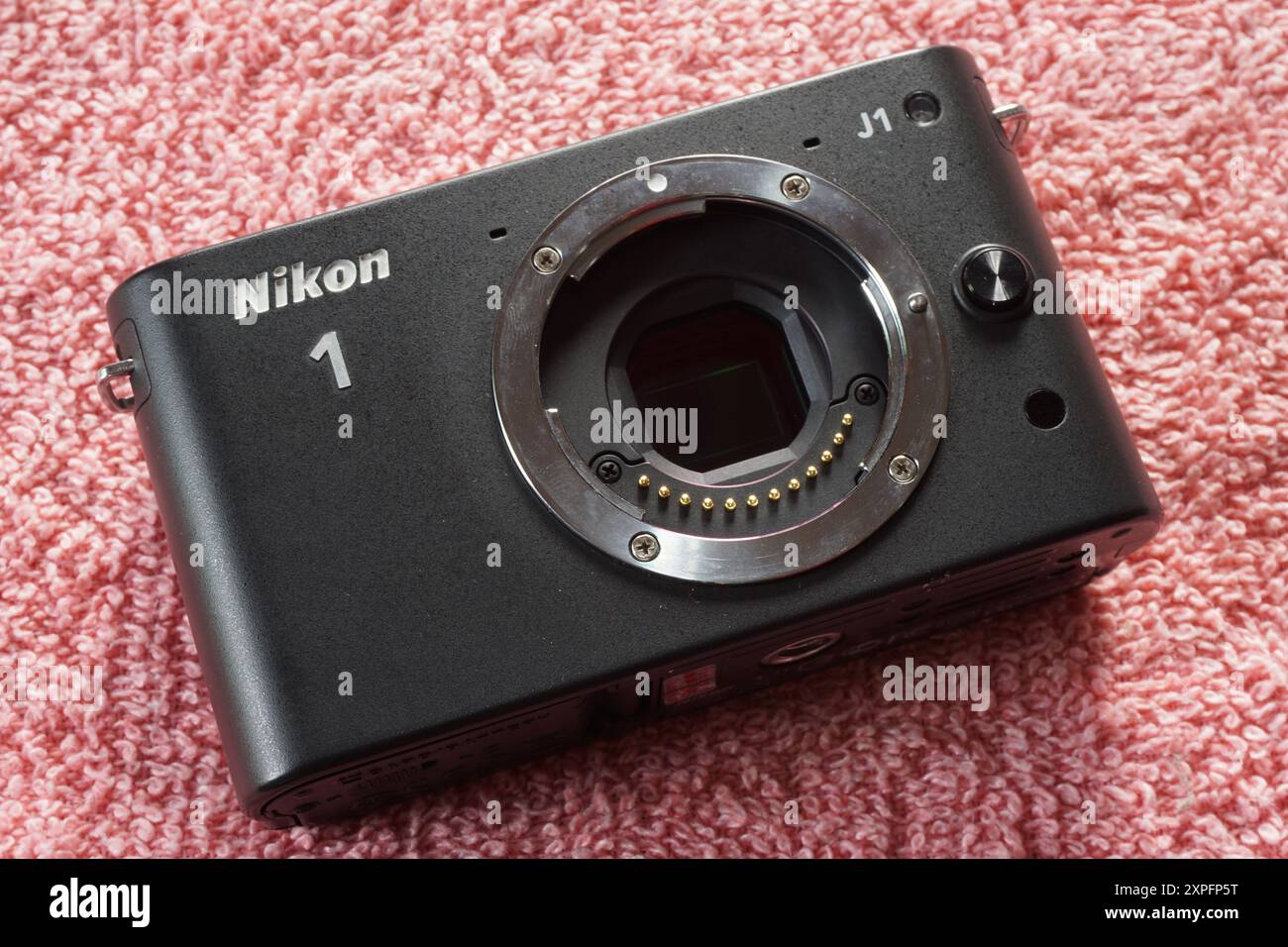 Terengganu, Malaysia - 23. August 2024 : Nahaufnahme der spiegellosen nikon 1 j1 Kamera auf rotem Hintergrund. Nikon 1 Zoll Kamerasensor. Stockfoto