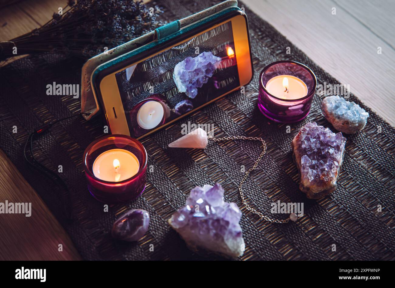 Video-Kurs der spirituellen Sitzung, Glückserzählung Live-Video über Smartphone-Konzept. Verschiedene geistige Gegenstände per Telefon. Kristallpendel, Kerze Stockfoto