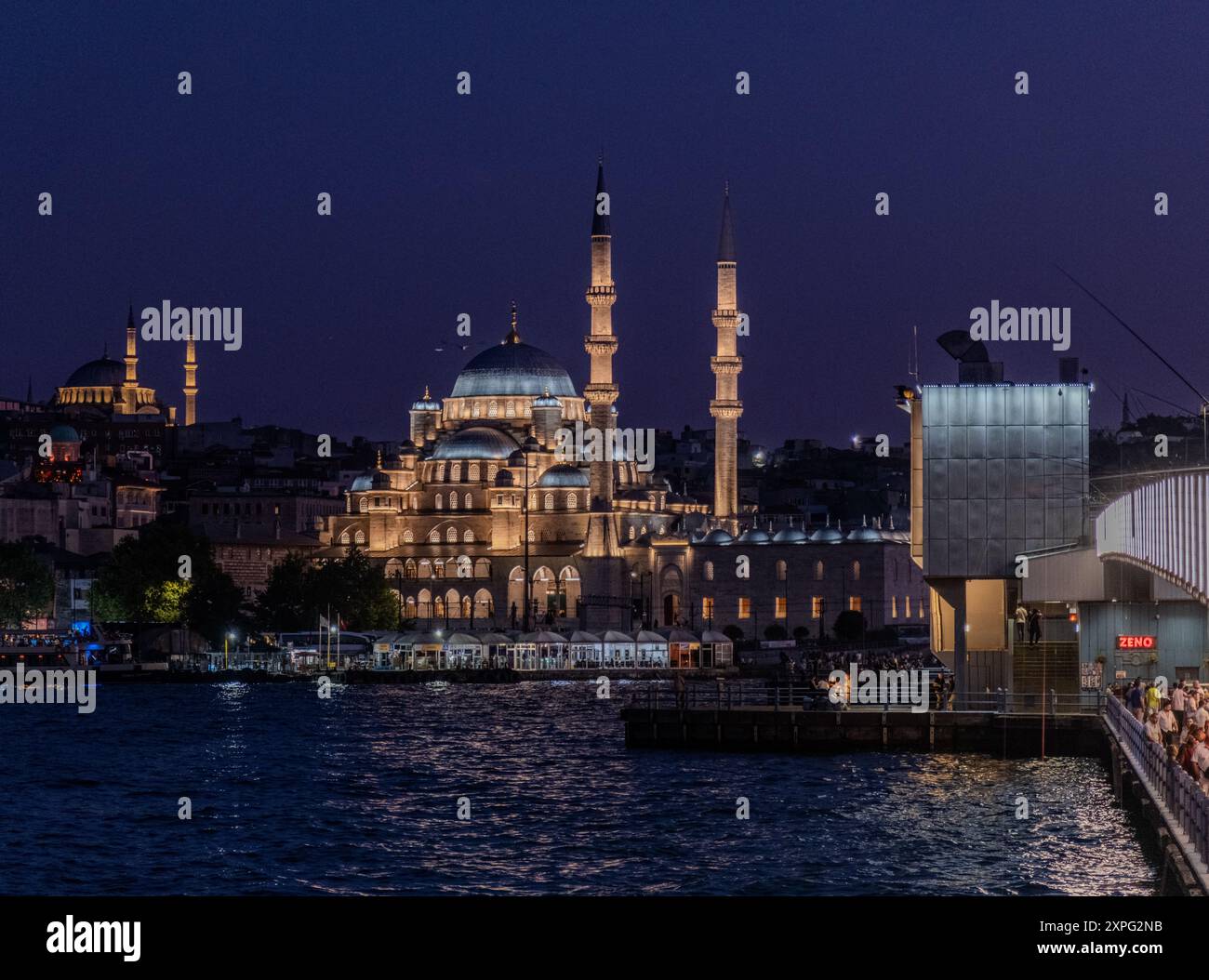 Nächtlicher Blick auf die berühmte neue Moschee (Yeni Camii) in Istanbul, Türkei, wunderschön beleuchtet, mit der Galata-Brücke im Vordergrund und der Stadtlandschaft Stockfoto