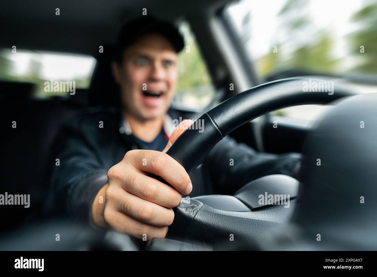 Schlechter Fahrer im Auto. Schockierter wütender Mann, der während der Fahrt geschrien hat. Straßenrausch. Bremsen bei einem Unfall mit hoher Geschwindigkeit. Schreiendes Taxi. Lustiges verrücktes Gesicht. Stockfoto