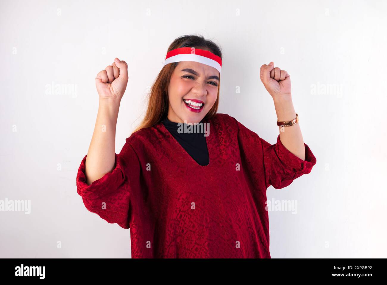 Eine asiatische Frau in rotem Kleid gibt ihren Ausdruck für den indonesischen Unabhängigkeitstag aus. Stockfoto