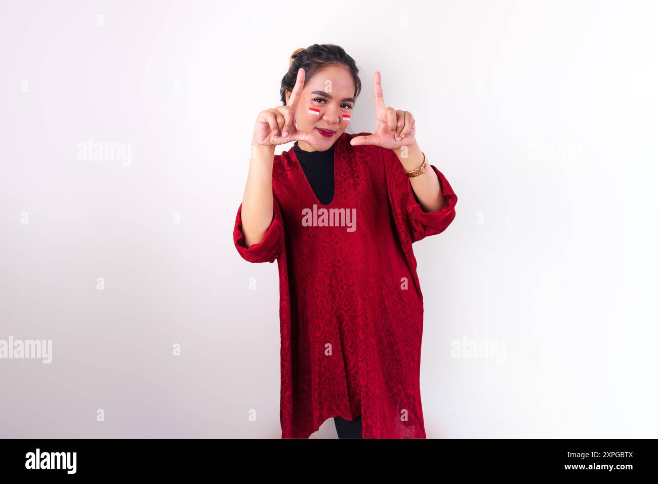 Eine asiatische Frau in rotem Kleid gibt ihren Ausdruck für den indonesischen Unabhängigkeitstag aus. Stockfoto