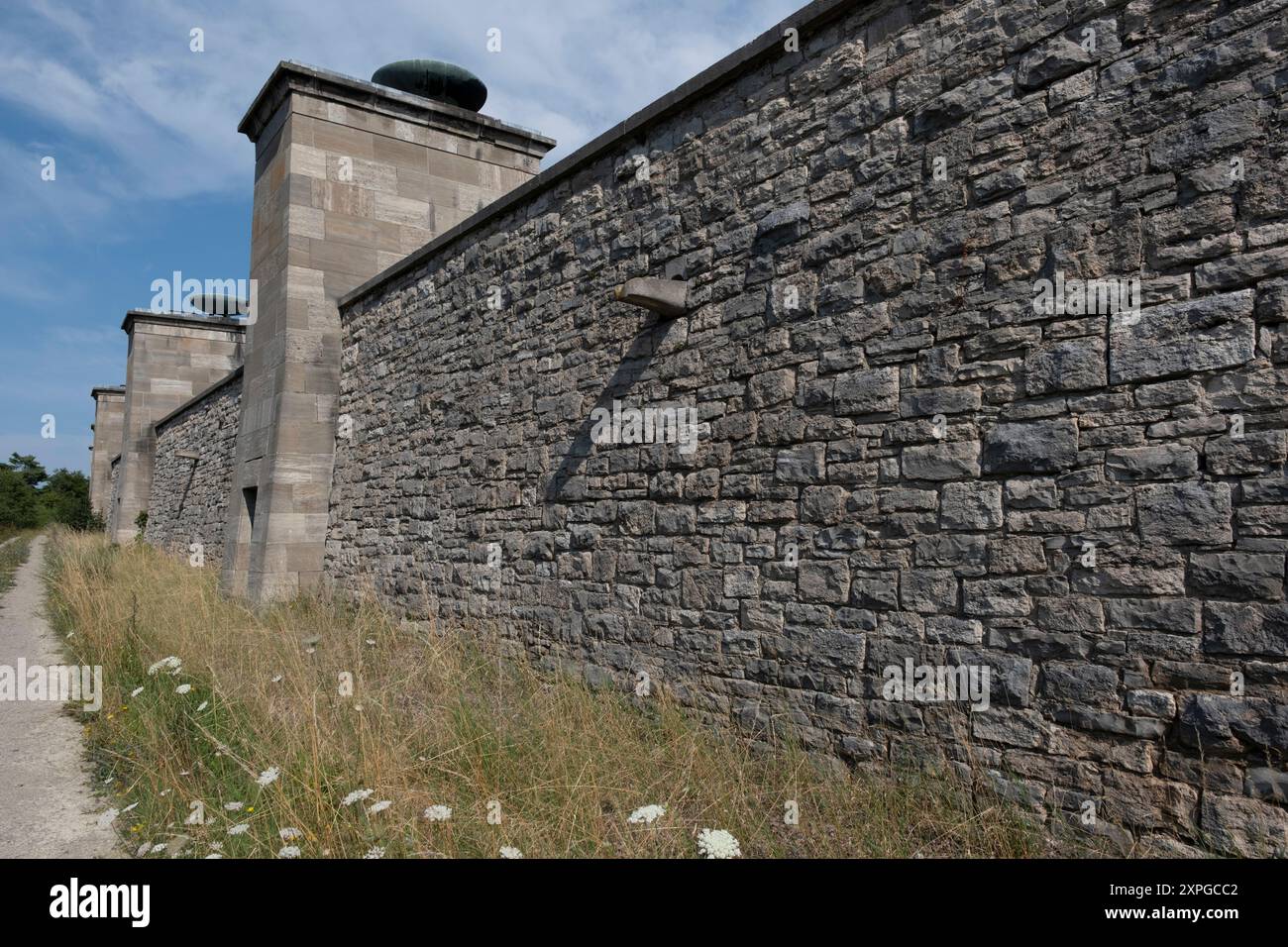 Gedenkstätte Buchenwald bei Weimar. Außenseite der Mauer mit Pylonen, auf denen regelmäßig Feuerschalen auf der neoklassischen „Straße der Nationen“ für nati beleuchtet werden Stockfoto