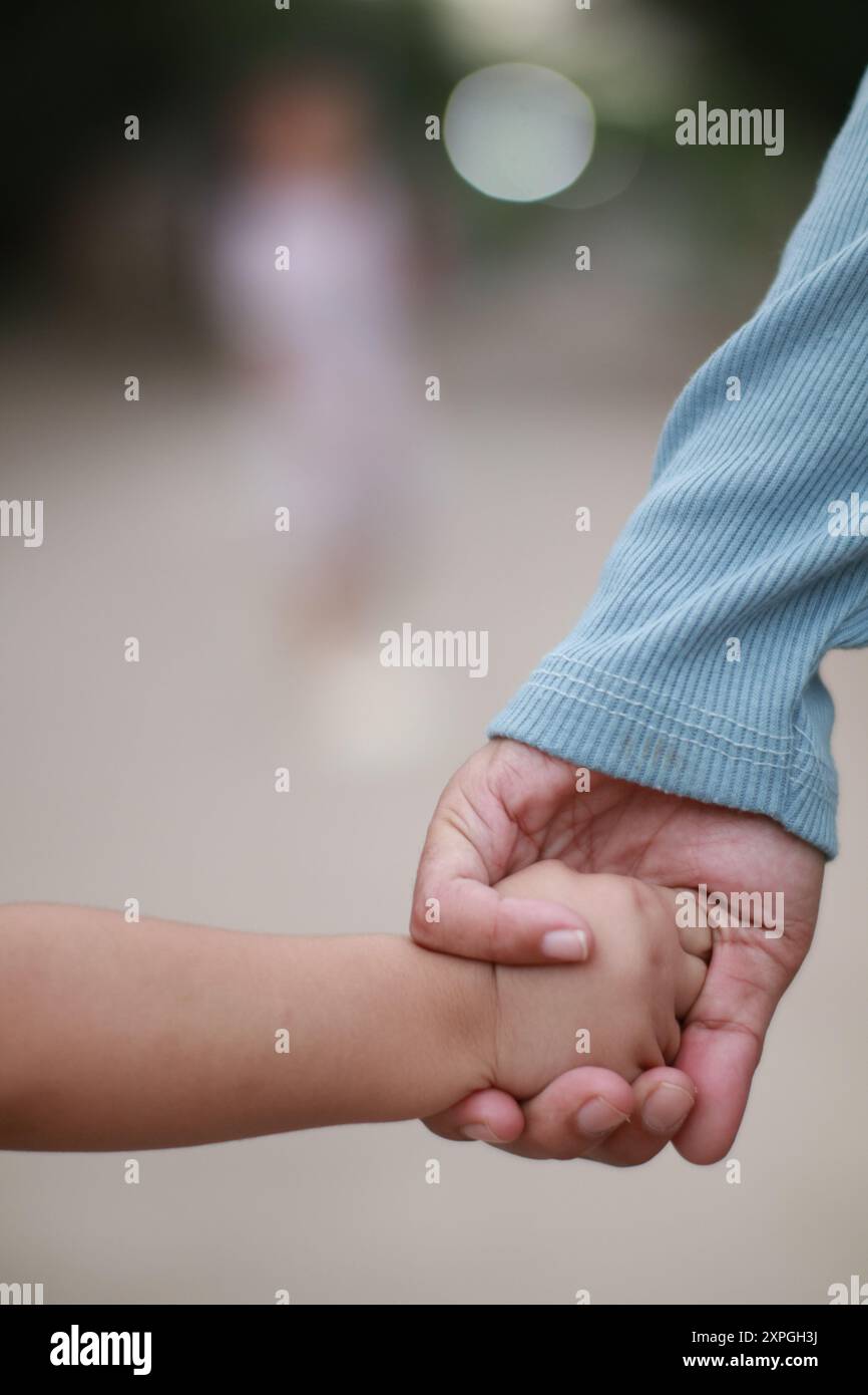 Eine Nahaufnahme einer Mutter, die eine Kinderhand hält, symbolisiert Fürsorge und Schutz Stockfoto