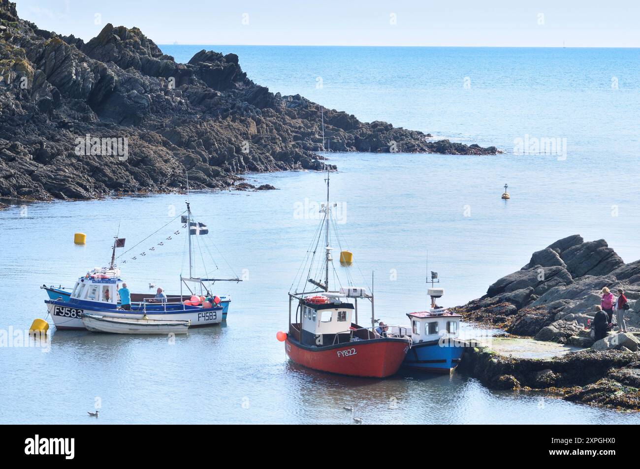 Traditionelle Fischerboote in der Nähe der Mündung des Hafens Polperro, die auch als Transport für touristische Bootsausflüge an der Küste Cornwalls dienen. Cornwall Großbritannien Stockfoto