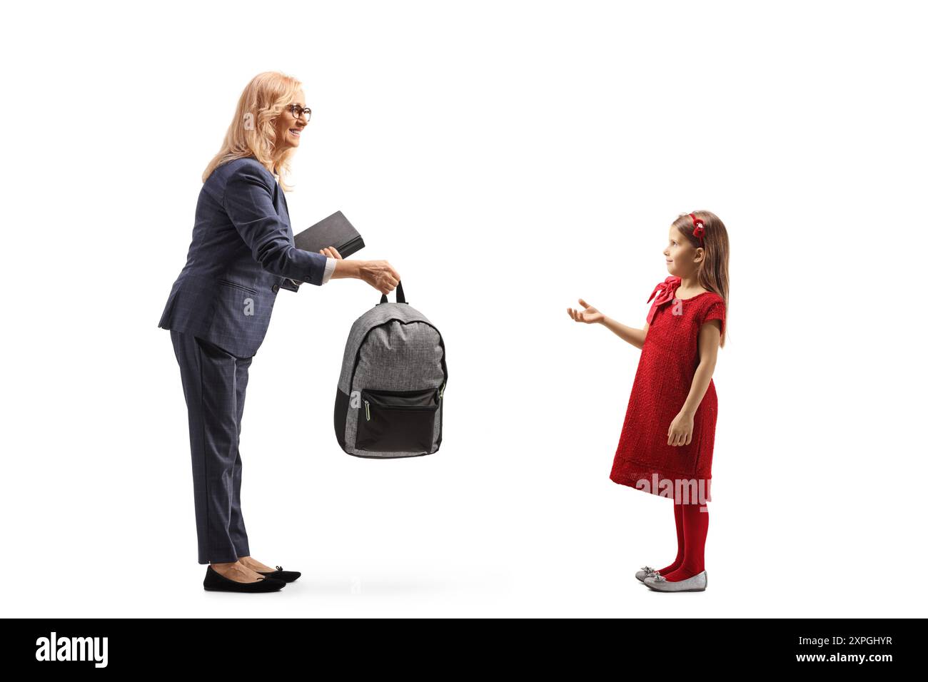 Ein Bild von einem Lehrer, der einem Mädchen auf weißem Hintergrund einen Rucksack gibt Stockfoto