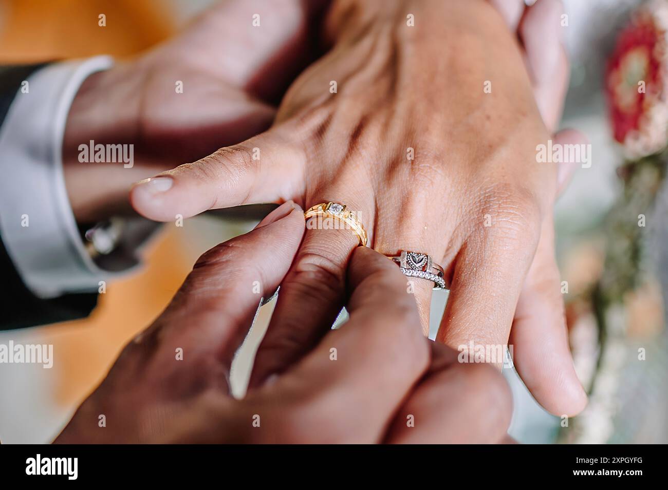 Der Bräutigam legt einen Ehering an den Ringfinger der Braut als Zeichen dafür, dass sie offiziell verheiratet sind Stockfoto