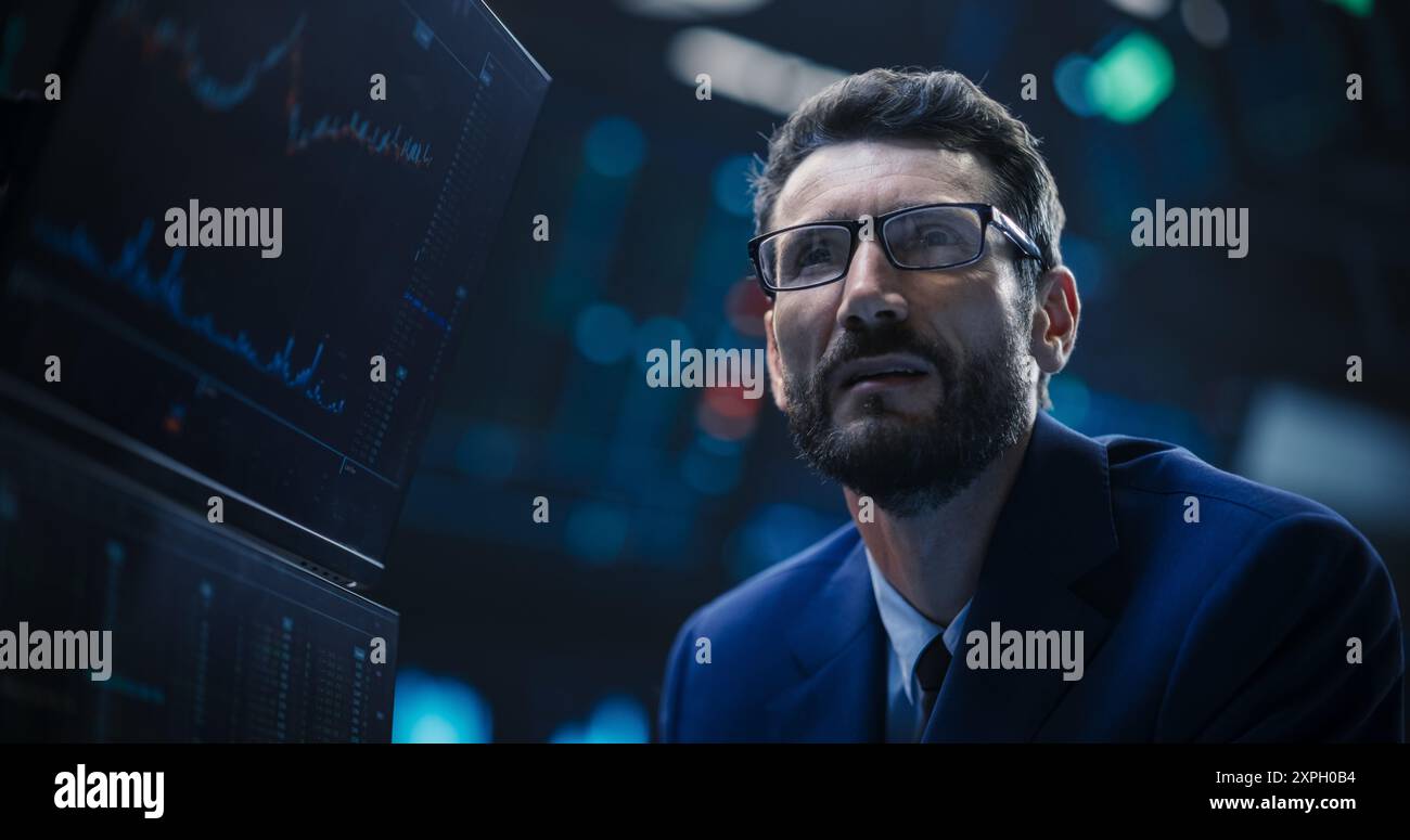Porträt eines gutaussehenden bärtigen Börsenhändlers, der in einer Börse arbeitet. Erwachsener Mann mit Brille, erforscht Investitionsmöglichkeiten für internationale Unternehmen Stockfoto