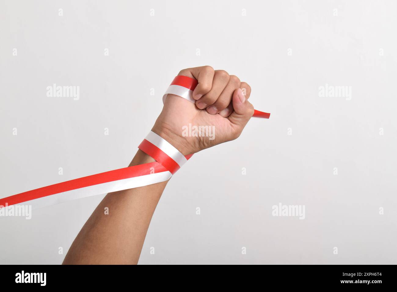 Die Hände werden mit roten und weißen Bändern als Symbol der indonesischen Flagge geballt, isoliert auf weißem Hintergrund. Indonesian Independence Day Concept, August Stockfoto