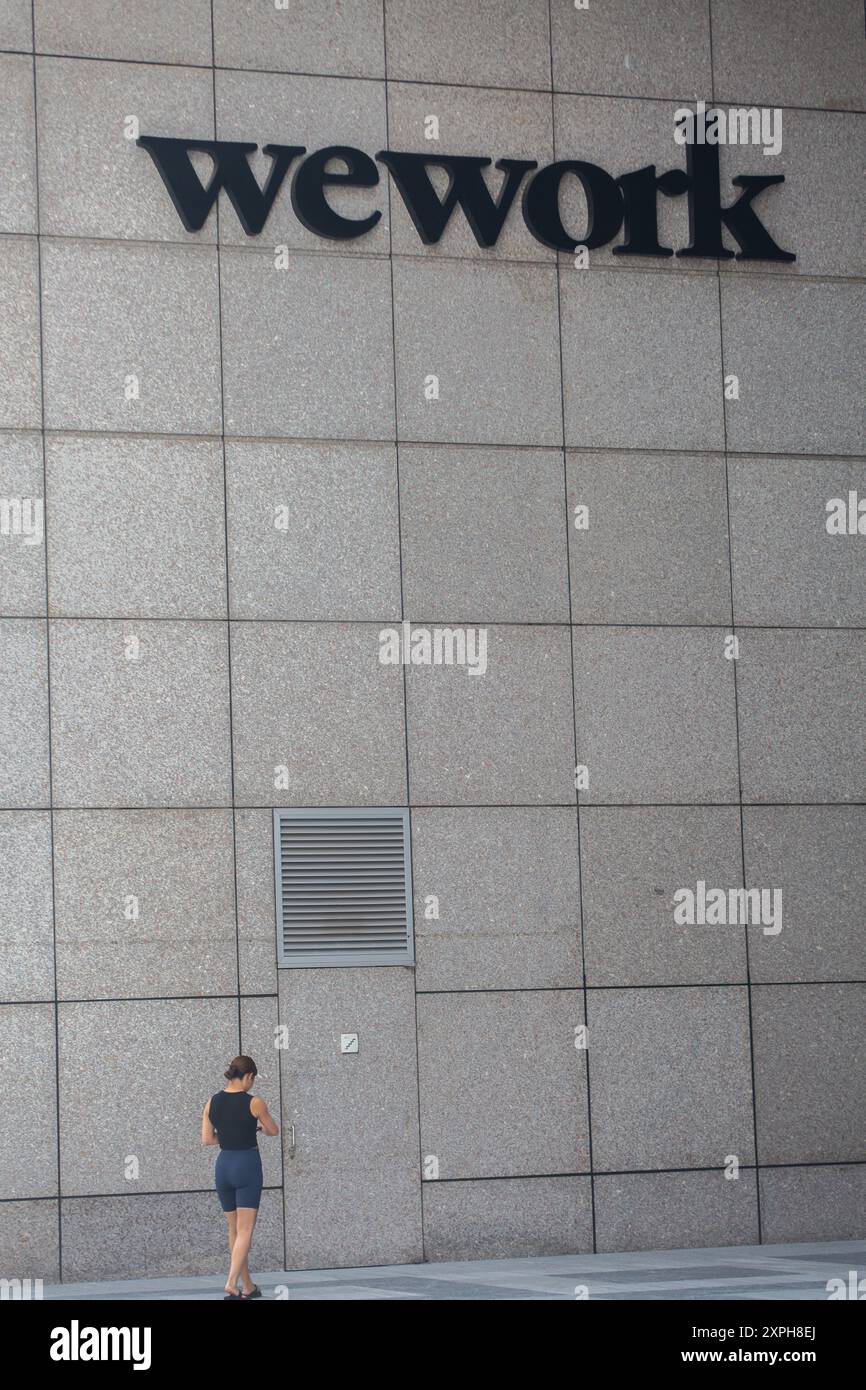 Eine Frau ging am WeWork-Logo vorbei, Singapur. Stockfoto