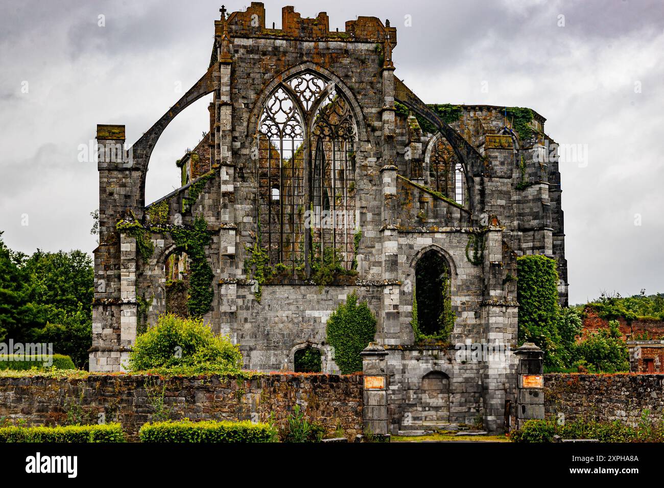 Vorderansicht des ruinierten ehemaligen Klostergebäudes von Aulne, Steinmauern, wilde grüne Vegetation und Bäume, stürmischer Himmel bedeckt mit Wolken im Hintergrund, bewölktes d Stockfoto