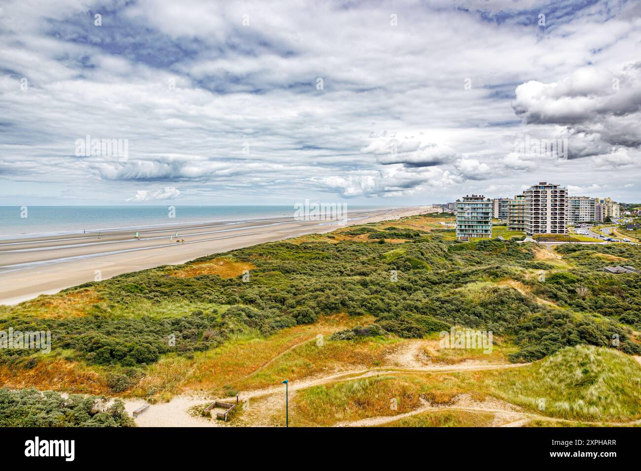 Panorama-Landschaft mit Dünen, Strand, Nordsee und Hochhäusern vor stürmischem Himmel bedeckt mit Wolken im Touristenzentrum de Panne, Horizont hinein Stockfoto