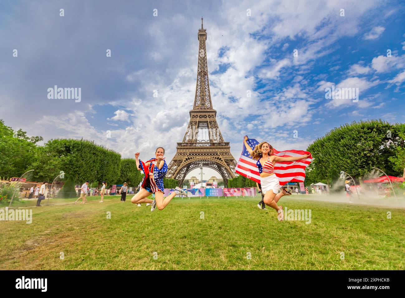 Patriotische Amerikanerin springt und jubelt für das Team USA und die Olympischen Spiele 2024 in Paris vor dem Eiffelturm, Paris, Frankreich, Europa Stockfoto