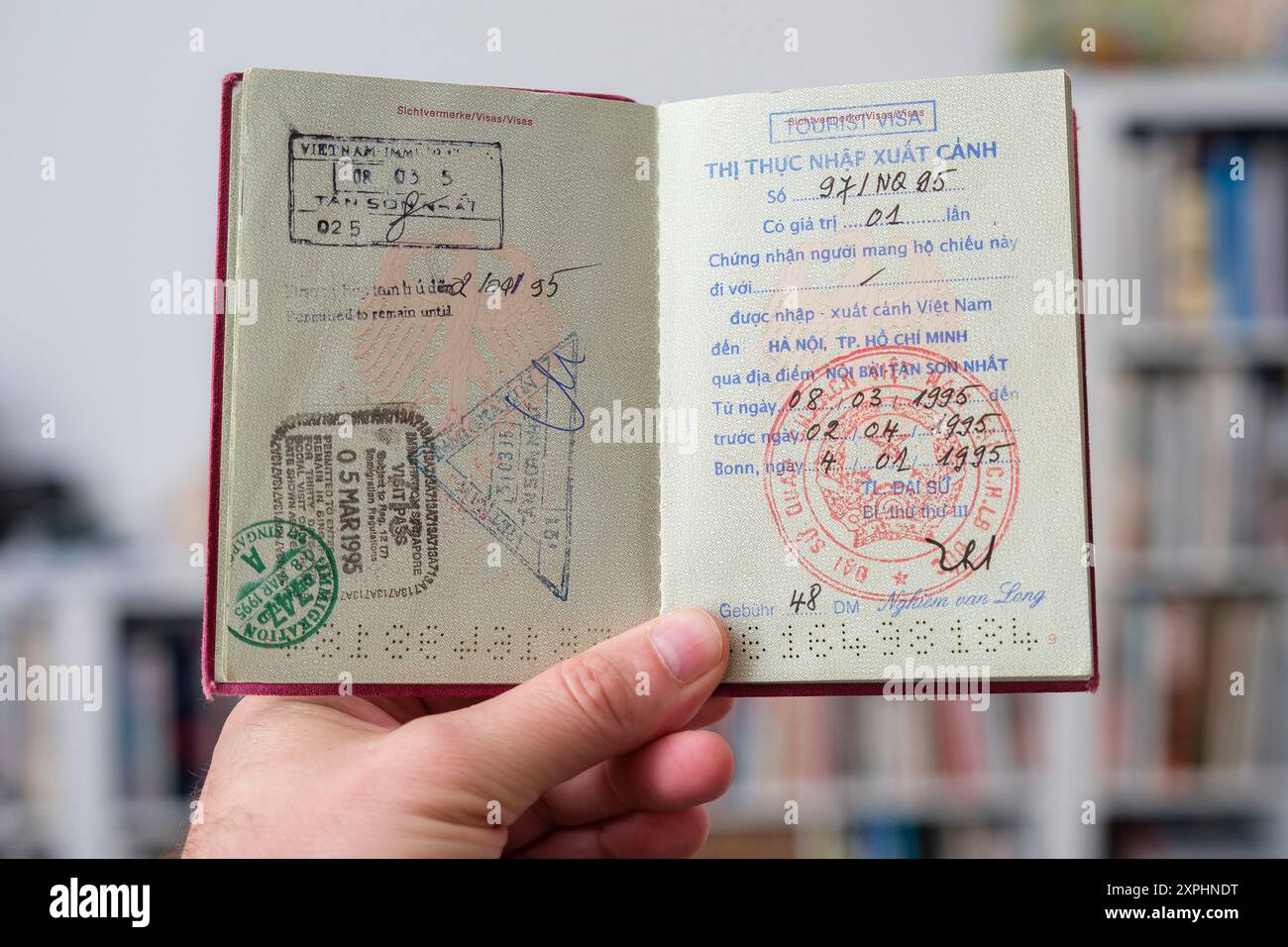 Hand hŠlt einen deutschen Reisepass mit Visa Stempeln von Vietnam*** Hand mit deutschem Reisepass mit Visumstempel Stockfoto