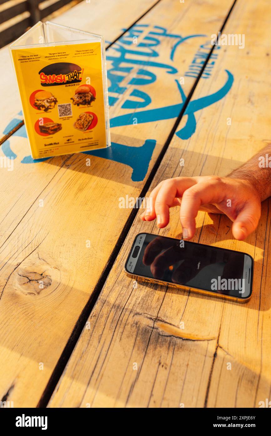 Mann bestellt Essen mit Telefon von Smash That, mit einem qr-Code bei der Dachbrauerei in Seattle Stockfoto