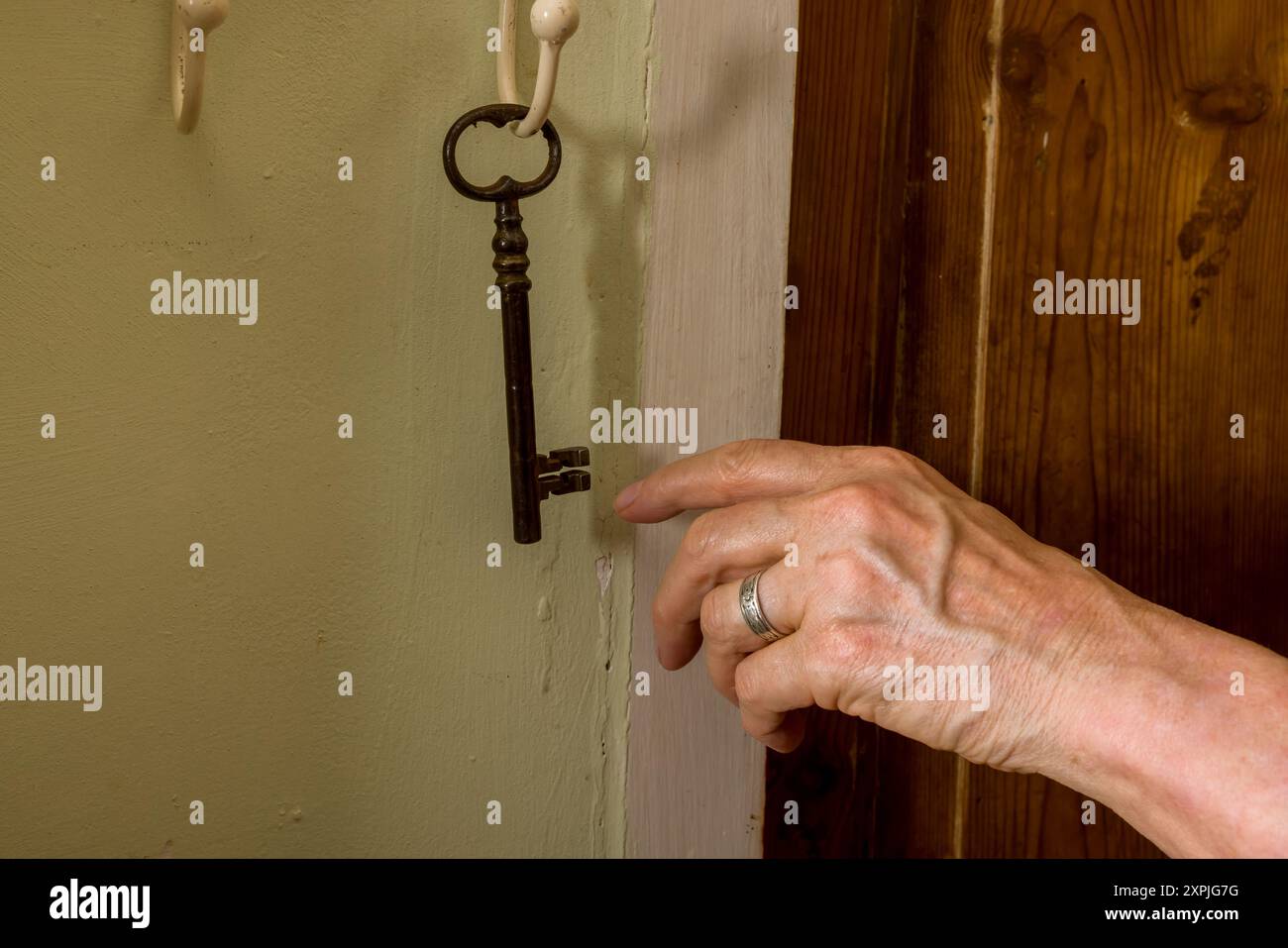 Die Hand greift nach einem rostigen alten Schlüssel Stockfoto