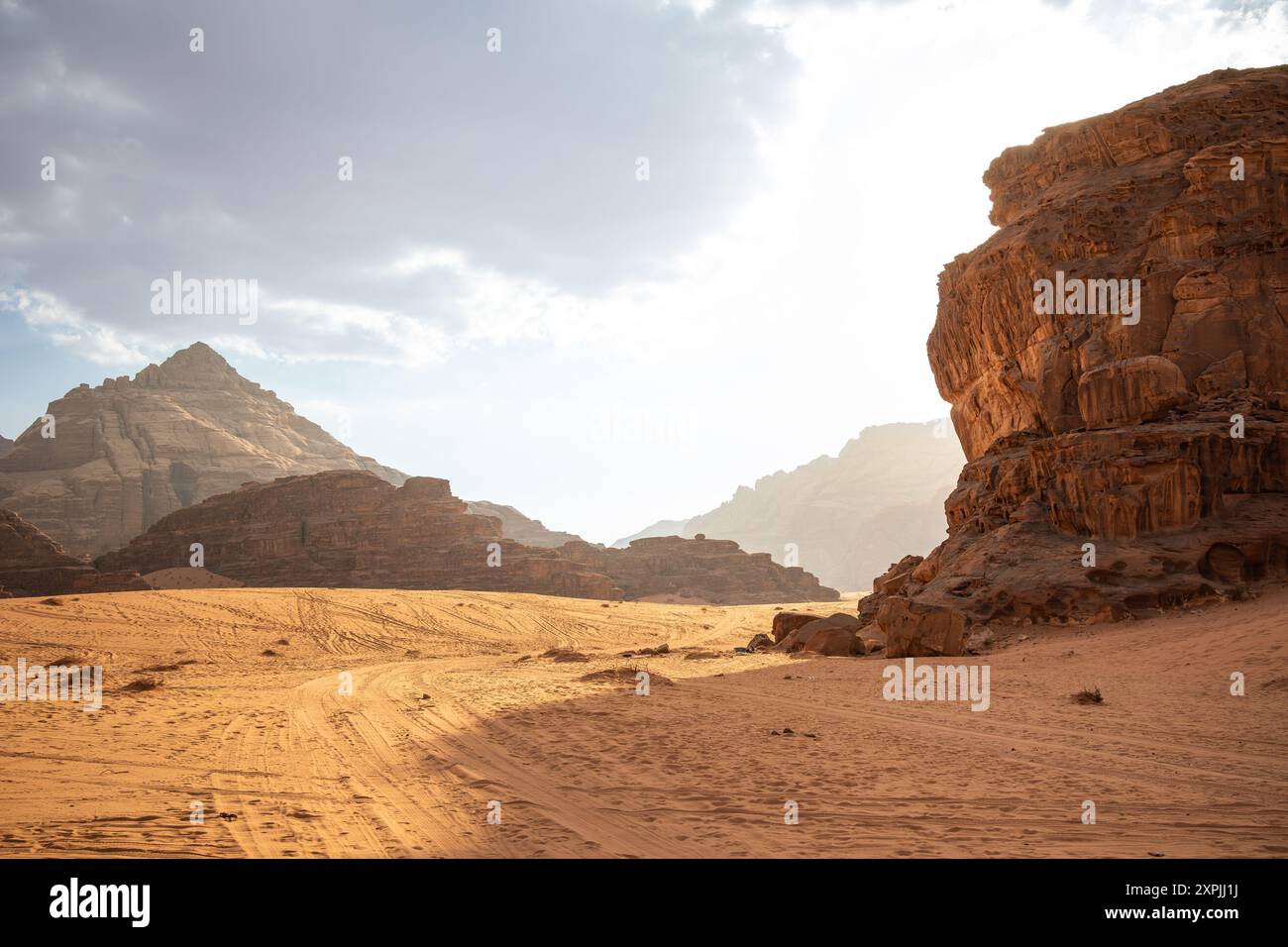 Jordanische Wüste mit Sandy Surface und Rocky Cliff im Nahen Osten. Wunderschöne Landschaft von Wadi Rum in Jordanien am Nachmittag. Stockfoto