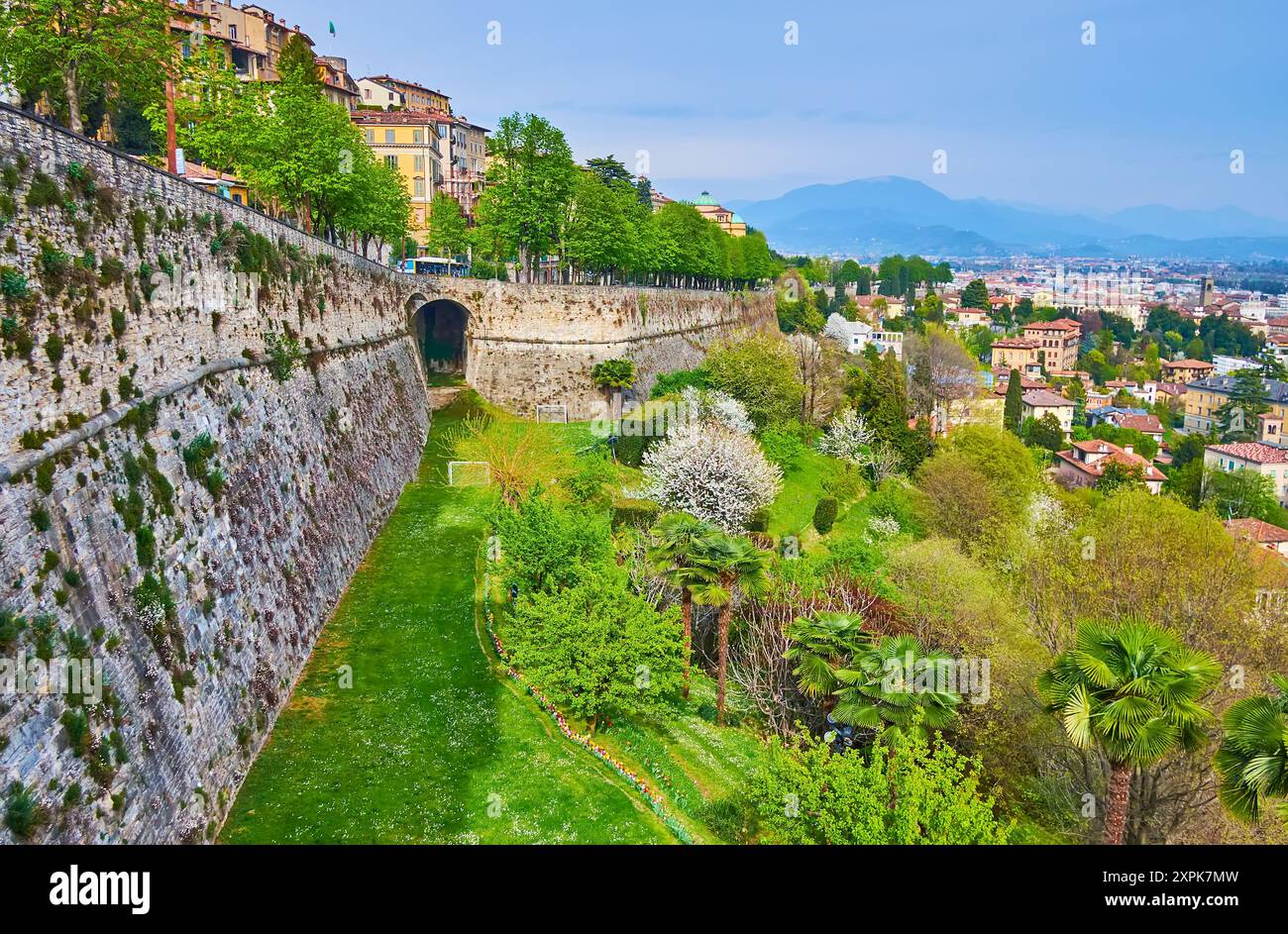 Der üppig grüne Park mit blühenden Frühlingsbäumen und Büschen am Fuße der venezianischen Mauern von Citta Alta, Bergamo, Italien Stockfoto