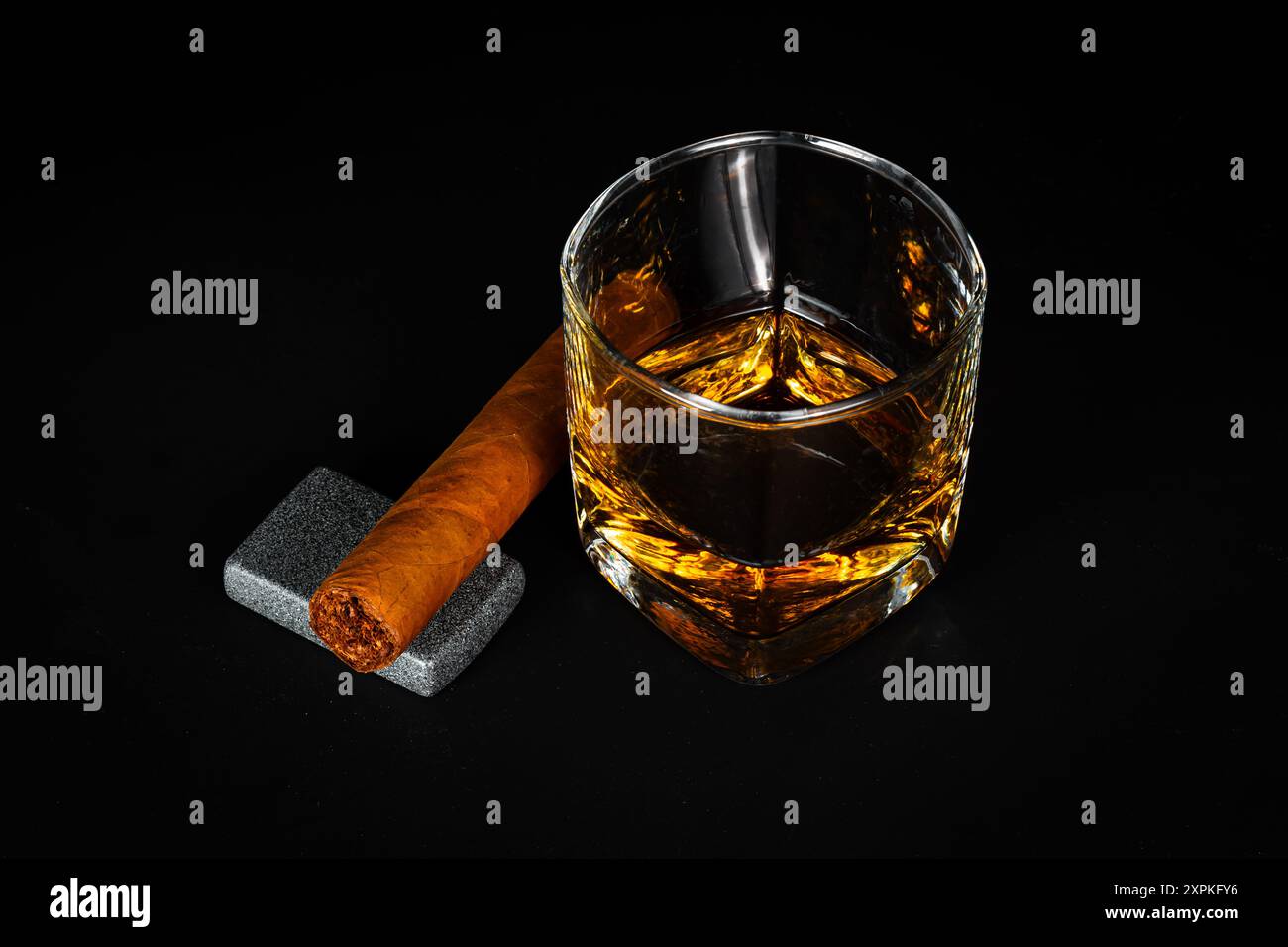 Ein Glas Scotch Whiskey mit einer unbeleuchteten Zigarre auf einem Zigarettenanzünder. Stockfoto