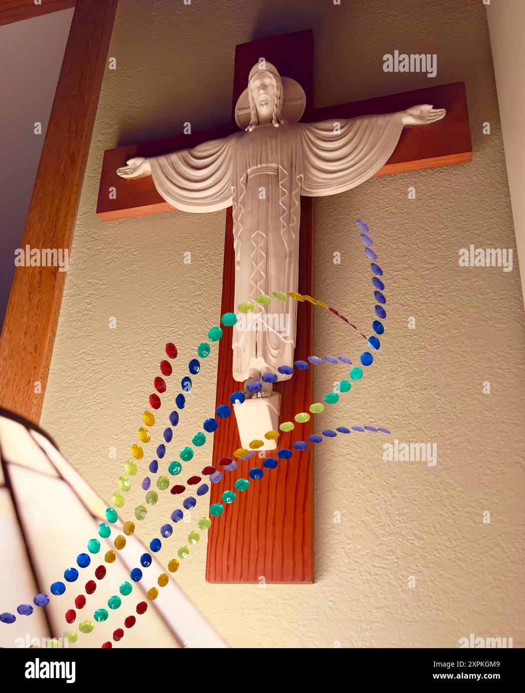 Jesus Christus ist auf einer Kreuzskulptur mit Licht aus der Lampe, die sein Gesicht beleuchtet. Der Heilige Geist strahlt Licht aus, wie die Strasssteine über dem Erlöser leuchten. Stockfoto