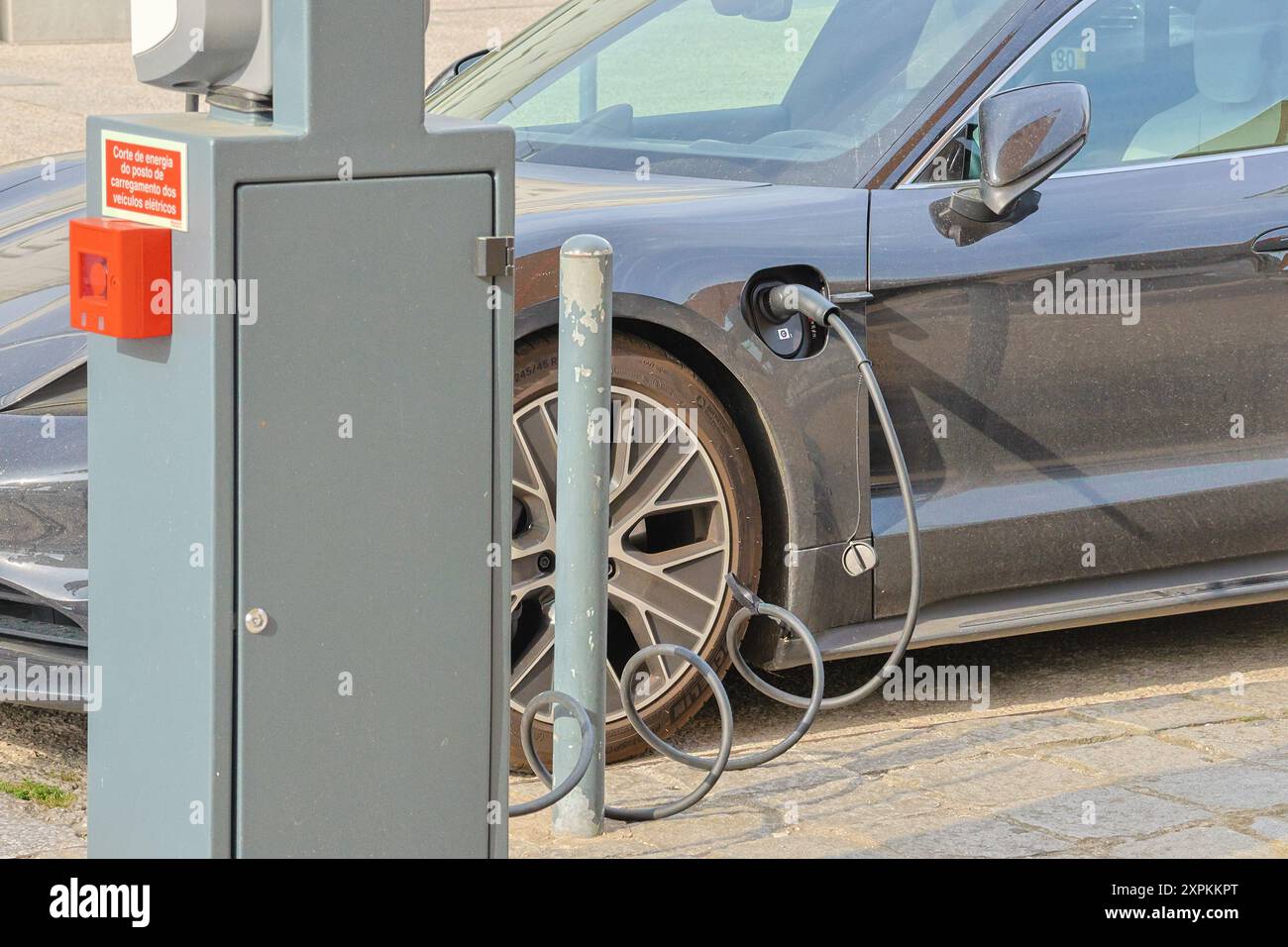 Modernes Elektroauto angeschlossen und an einer städtischen Ladestation aufgeladen Stockfoto