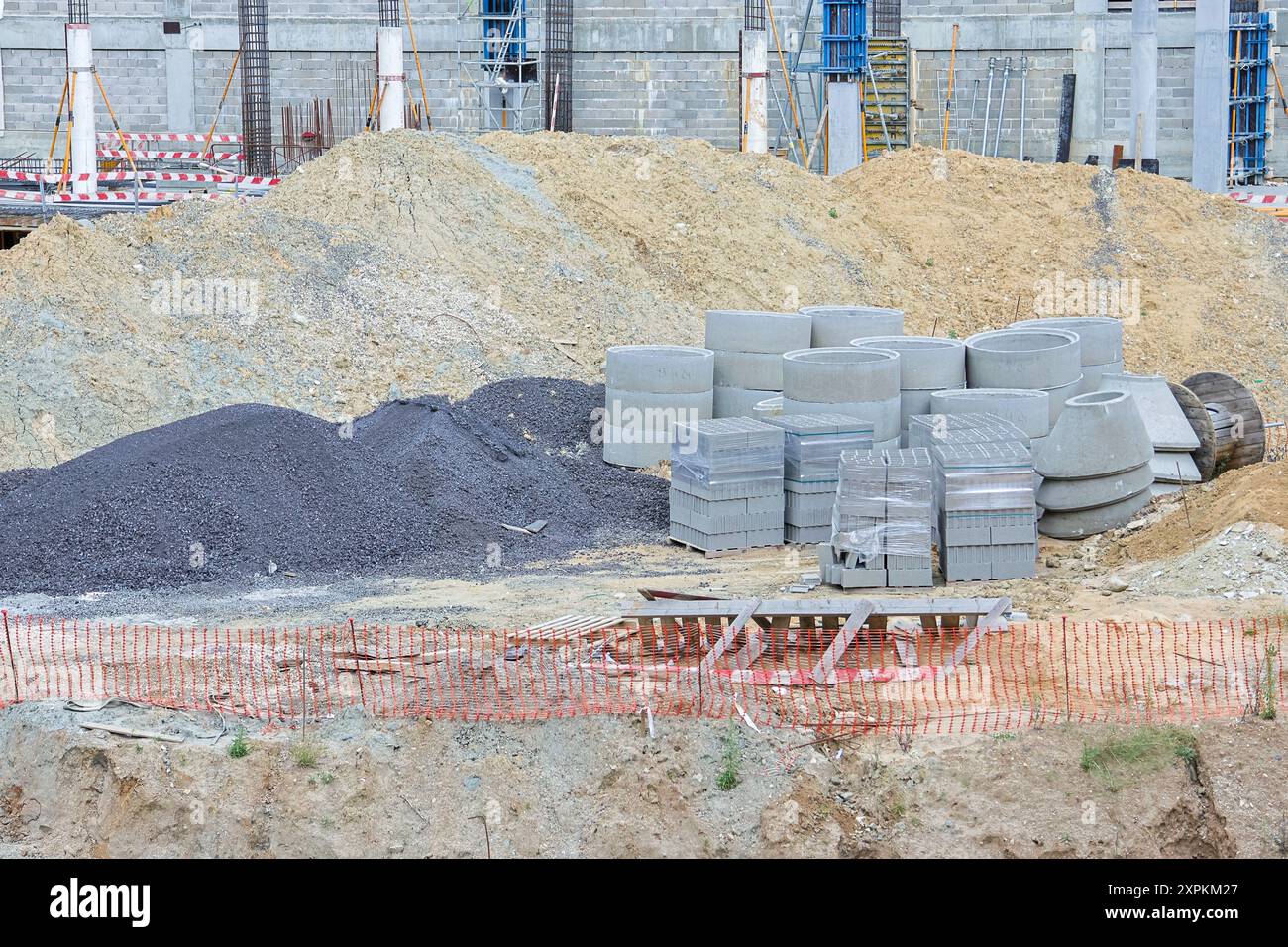 Kies- und Sandstapel mit Betonringen und -Blöcken auf einer Baustelle Stockfoto