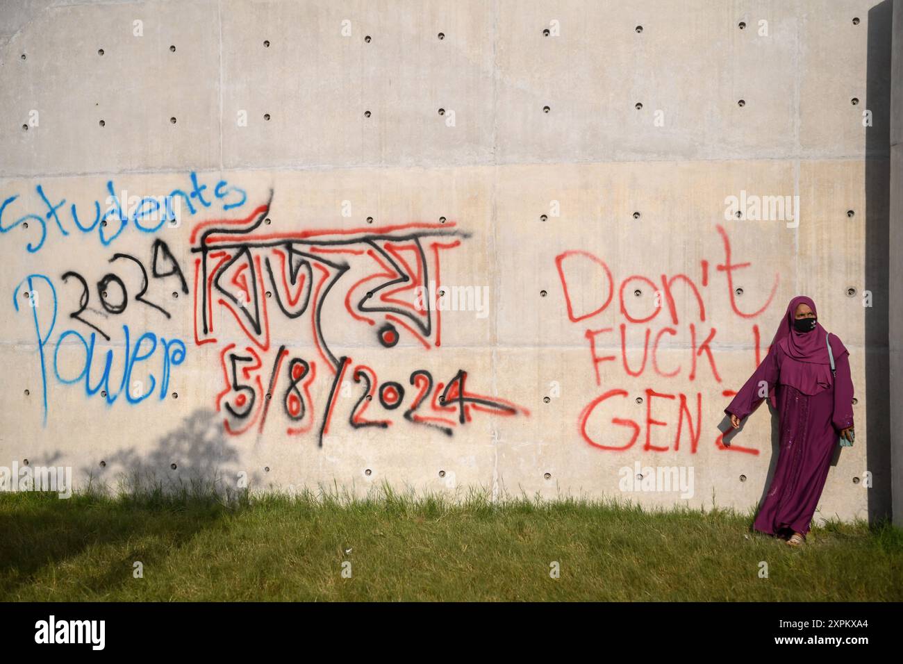 Dhaka, Bangladesch. August 2024. Dhaka, Bangladesch. August 2024. Fußgänger steht nach einem Protest vor einer beschädigten Mauer. Am 5. August trat Sheikh Hasina aus dem Amt des Premierministers von Bangladesch zurück und flog von Bangladesch nach Indien. Quelle: SOPA Images Limited/Alamy Live News Stockfoto