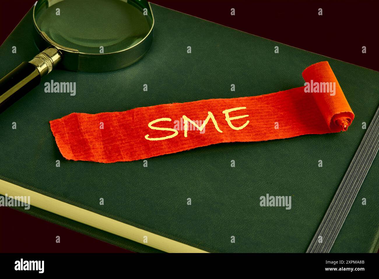 KMU, kleine und mittlere Unternehmen. KMU auf einem roten Blatt Papier, das auf einem grünen Geschäftsbuch liegt Stockfoto