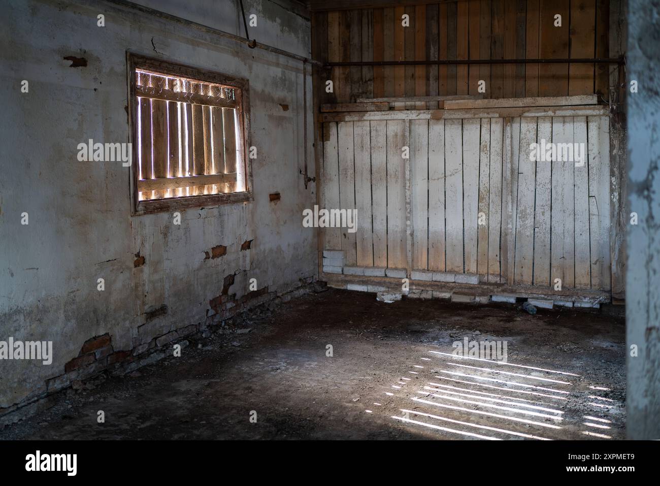 Innenraum einer verlassenen Fischfabrik mit Holzwand. Weiß getünchte Wände im alten Fabrikgebäude. Stockfoto