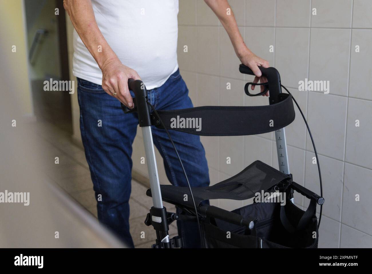 Ein aelterer Mann laeuft mit einem Rollator durch einen Hausflur in Berlin, 05.08.2024. Berlin Deutschland *** ein älterer Mann geht mit einem Geher durch einen Flur in Berlin, 05 08 2024 Berlin Deutschland Copyright: XKiraxHofmann/photothek.dex Stockfoto